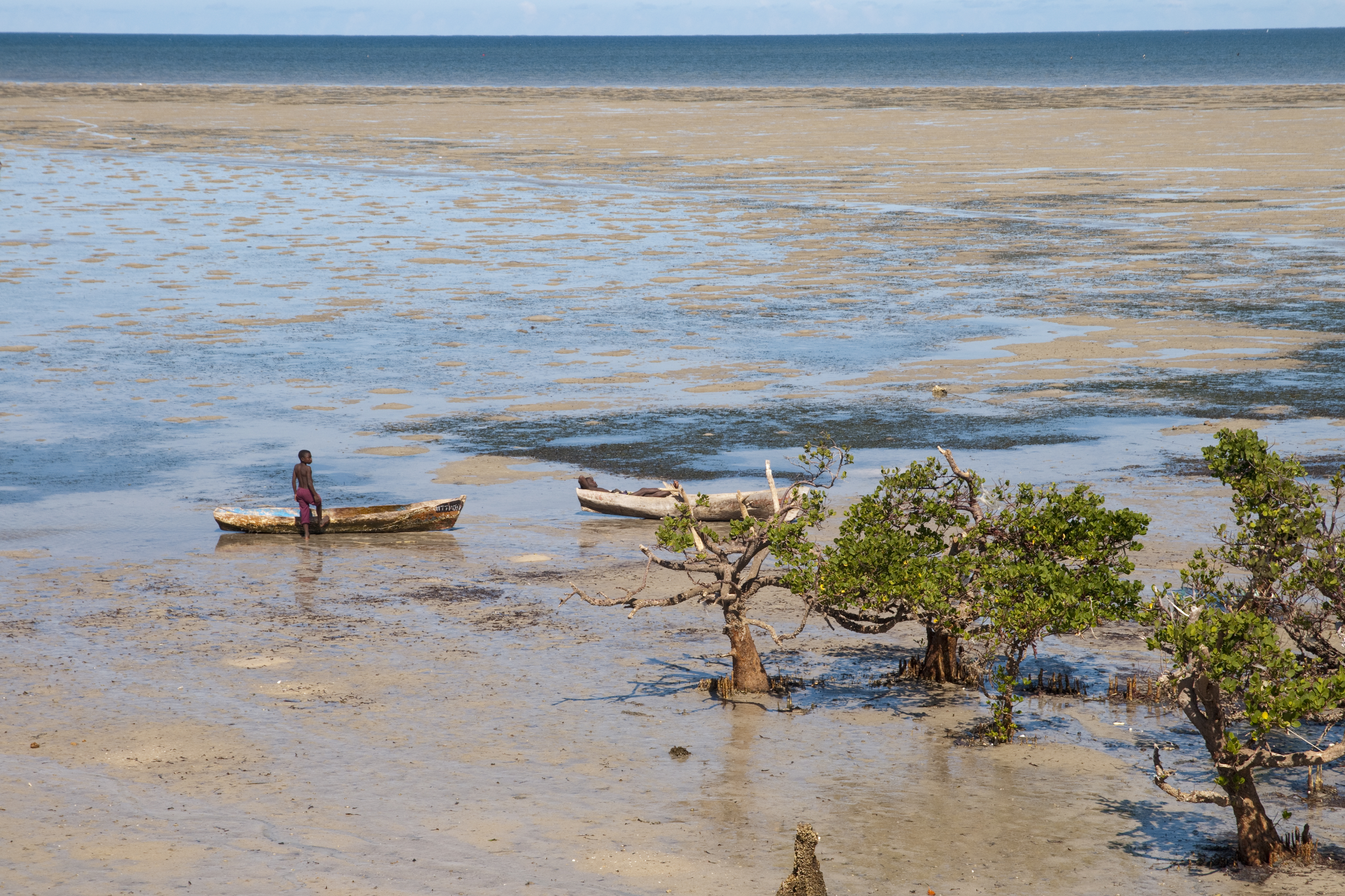 People with small boats among mangroves at low tide on Ilha de Moçambique